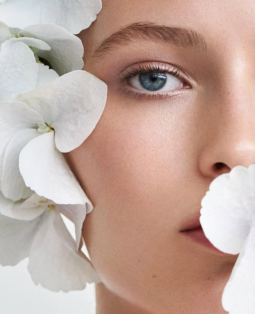 Woman's face with white flowers, the ingredients behind today's most talked-about skincare