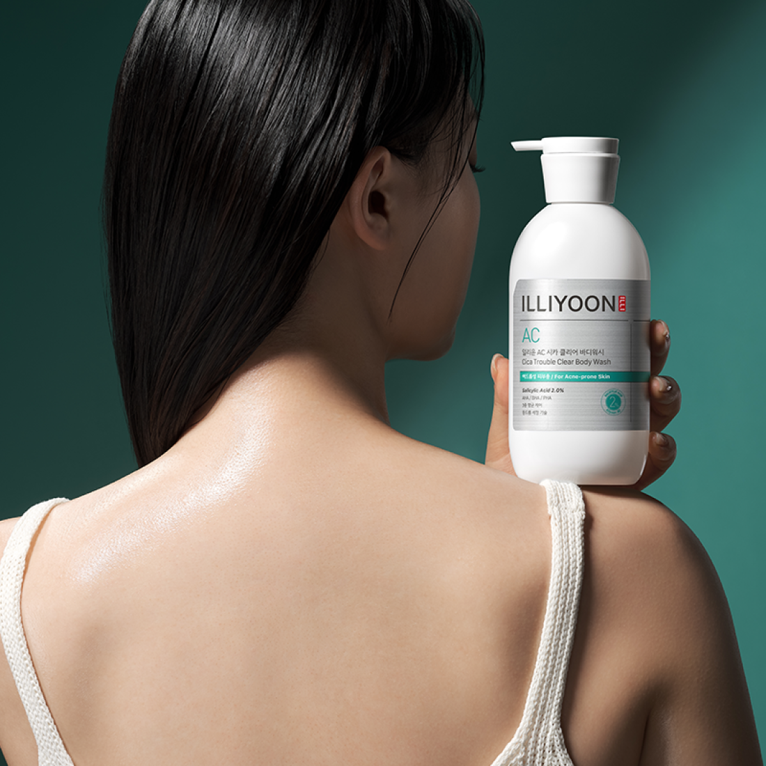 Woman holding a bottle of Illiyoon Body skincare product against a green background, Body care lotion and wash for smooth skin, LUME