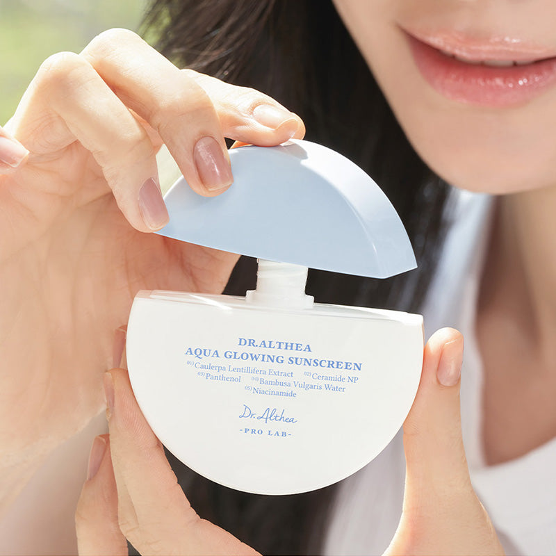 Person holding a Dr. Akthea Aqua Glowing sunscreen product, Korean sunscreen for daily sun protection, LUME